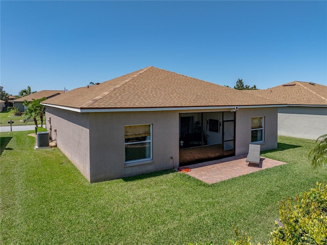 rear view of house featuring stucco siding, roof with shingles, central AC, a yard, and a patio area