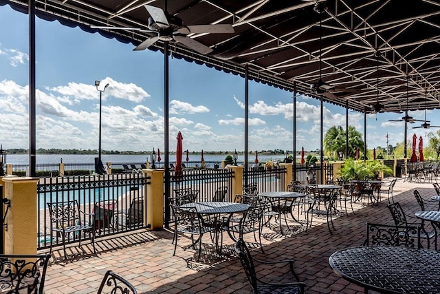 view of patio / terrace with ceiling fan, a water view, and fence