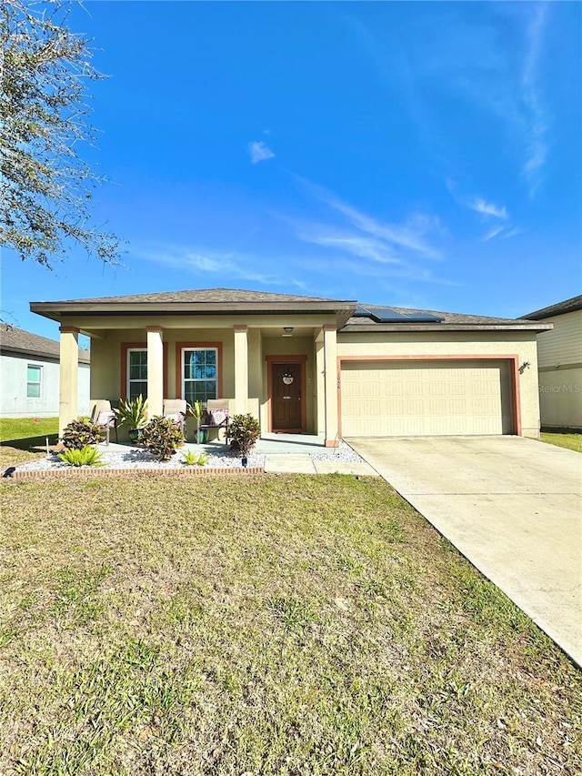 view of front facade with stucco siding, a front lawn, concrete driveway, an attached garage, and solar panels