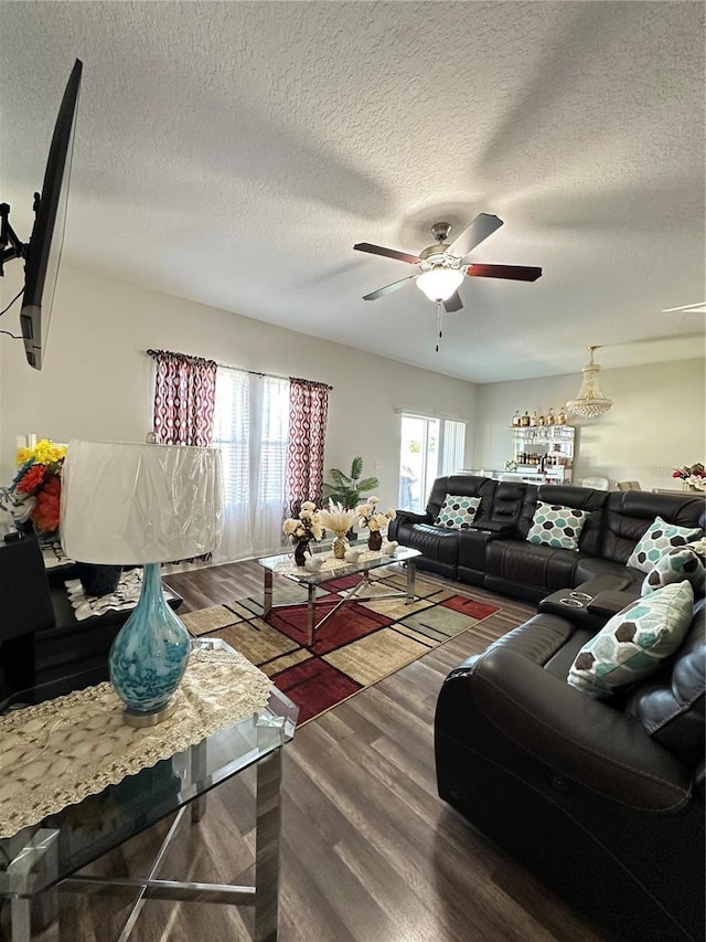 living room with a textured ceiling, ceiling fan, and wood finished floors