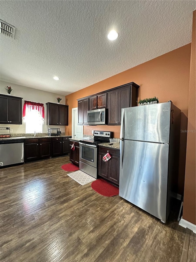 kitchen with visible vents, dark wood-style flooring, stainless steel appliances, dark brown cabinetry, and a textured ceiling