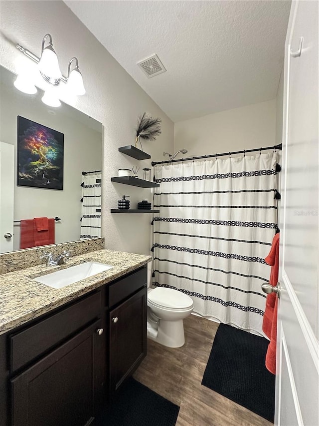 full bathroom with visible vents, toilet, a textured ceiling, wood finished floors, and vanity