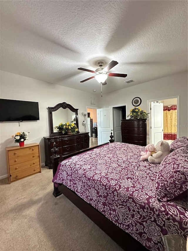 bedroom featuring carpet flooring, a ceiling fan, visible vents, and a textured ceiling