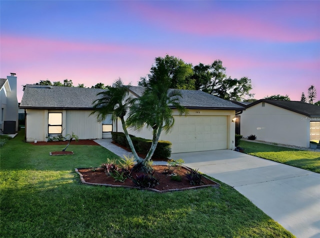 single story home featuring a yard, a garage, driveway, and stucco siding