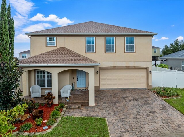 view of front of home featuring decorative driveway, fence, a garage, and stucco siding