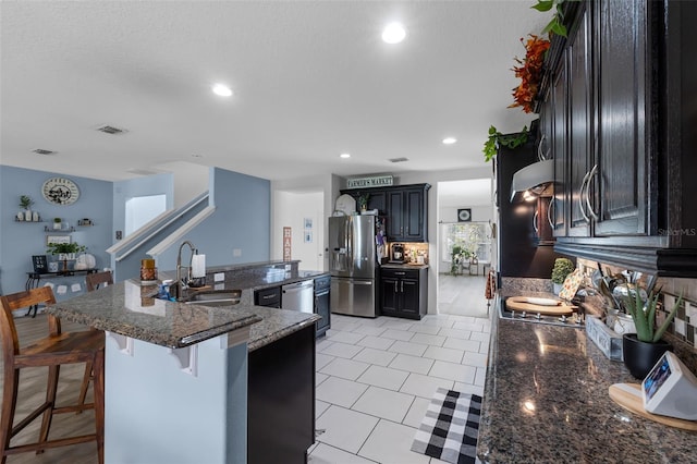 kitchen with light tile patterned floors, visible vents, a sink, appliances with stainless steel finishes, and a kitchen breakfast bar