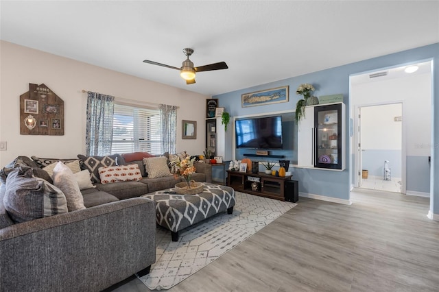 living area with visible vents, baseboards, a ceiling fan, and wood finished floors