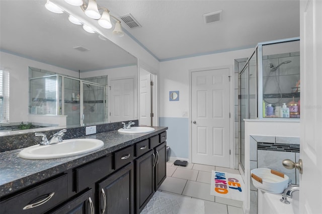 full bathroom featuring tile patterned flooring, a stall shower, visible vents, and a sink