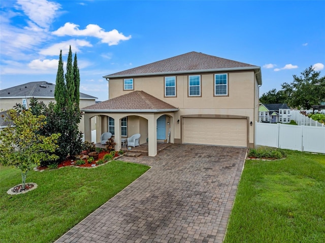 view of front facade with fence, a front yard, covered porch, stucco siding, and decorative driveway