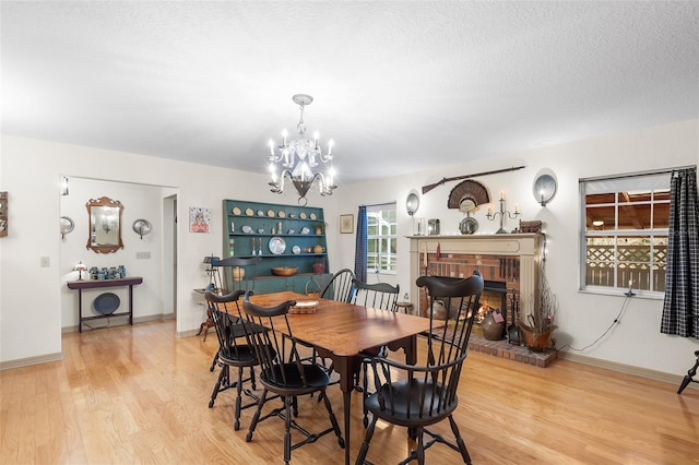 5020 Broadmore Dr, Auburndale, FL 33823 - dining room with light wood-type flooring, a chandelier, a brick fireplace, a textured ceiling, and baseboards