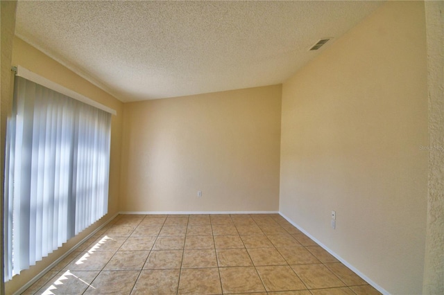 empty room featuring light tile patterned flooring, a textured ceiling, baseboards, and visible vents