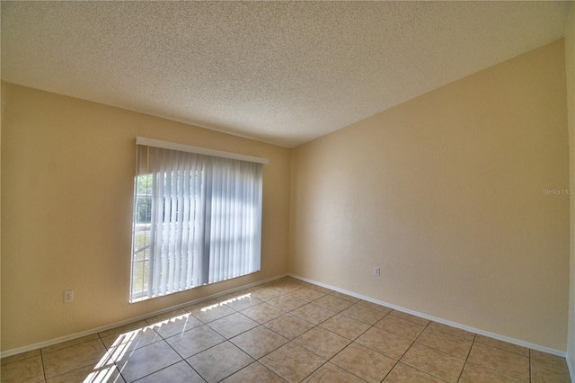 unfurnished room with light tile patterned floors, baseboards, and a textured ceiling