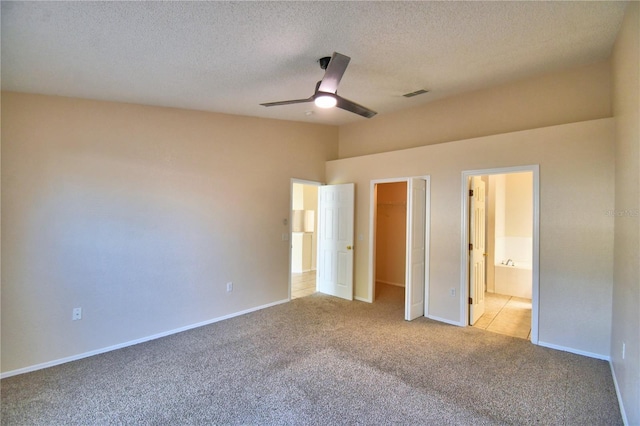 unfurnished bedroom with a walk in closet, carpet, connected bathroom, visible vents, and a closet