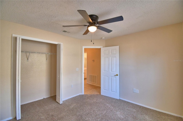 unfurnished bedroom featuring a closet, a textured ceiling, visible vents, ceiling fan, and carpet floors