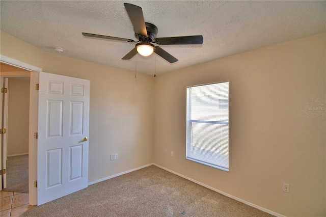 unfurnished bedroom featuring baseboards, a textured ceiling, ceiling fan, and light colored carpet