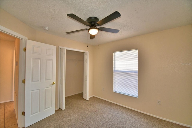 unfurnished bedroom with a ceiling fan, a closet, light colored carpet, and a textured ceiling