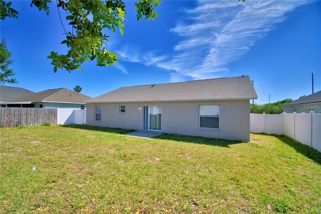 rear view of property featuring a fenced backyard, a lawn, and stucco siding