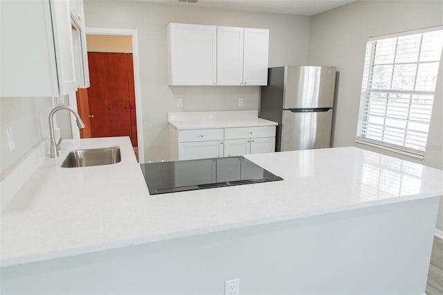 1801 3rd Ct SE, Winter Haven, FL 33880 - kitchen with freestanding refrigerator, a sink, stovetop, white cabinetry, and a peninsula