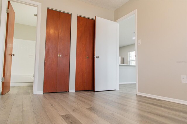 1801 3rd Ct SE, Winter Haven, FL 33880 - unfurnished bedroom with light wood-type flooring, multiple closets, and baseboards