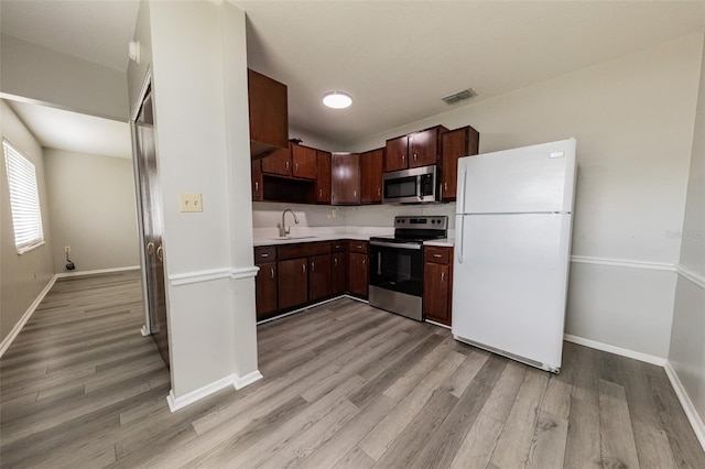 1801 3rd Ct SE, Winter Haven, FL 33880 - kitchen featuring appliances with stainless steel finishes, a sink, light wood finished floors, light countertops, and baseboards
