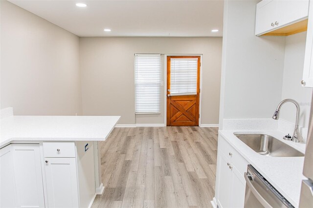 1801 3rd Ct SE, Winter Haven, FL 33880 - kitchen with a sink, stainless steel dishwasher, light countertops, light wood finished floors, and white cabinetry