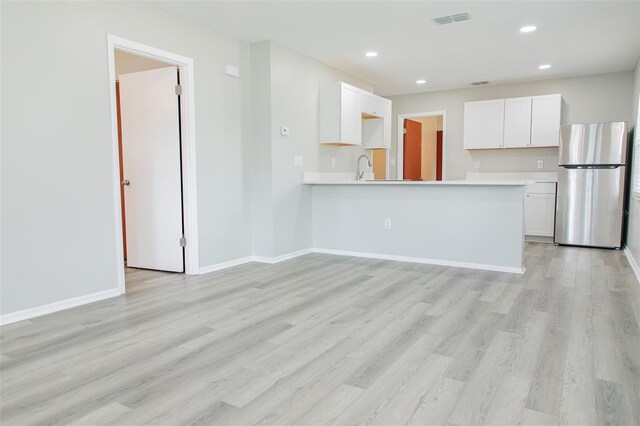 1801 3rd Ct SE, Winter Haven, FL 33880 - kitchen with freestanding refrigerator, white cabinets, light wood-type flooring, light countertops, and recessed lighting