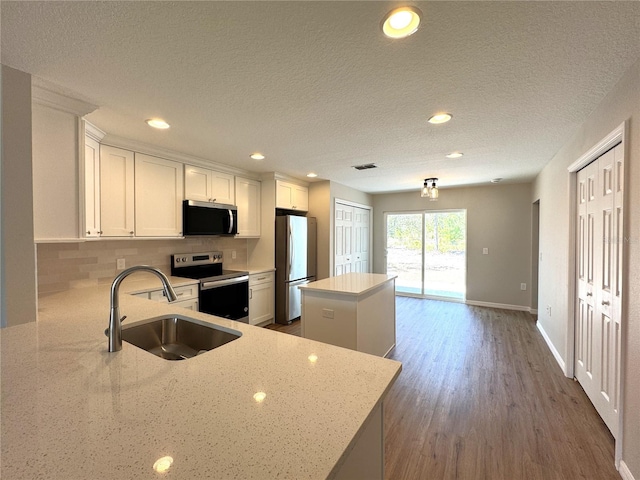 kitchen with a sink, tasteful backsplash, a center island, stainless steel appliances, and white cabinets