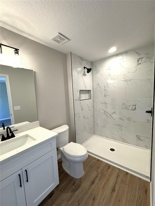 full bath with visible vents, toilet, wood finished floors, vanity, and a stall shower