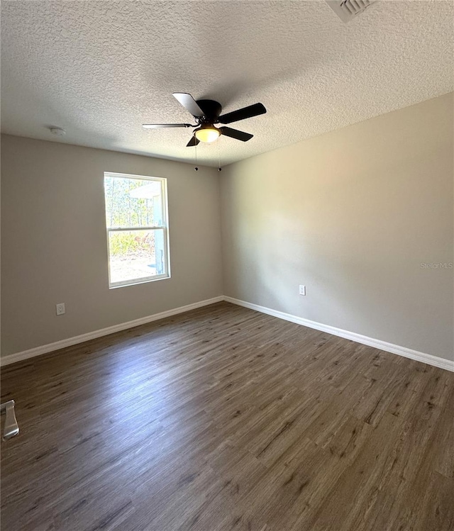 spare room with baseboards, a textured ceiling, ceiling fan, and dark wood finished floors