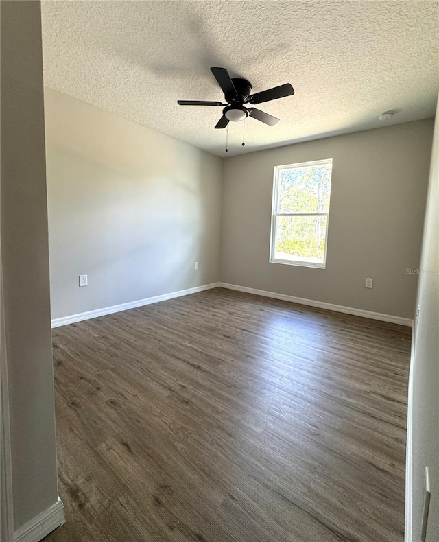 spare room with baseboards, a textured ceiling, dark wood-style floors, and a ceiling fan