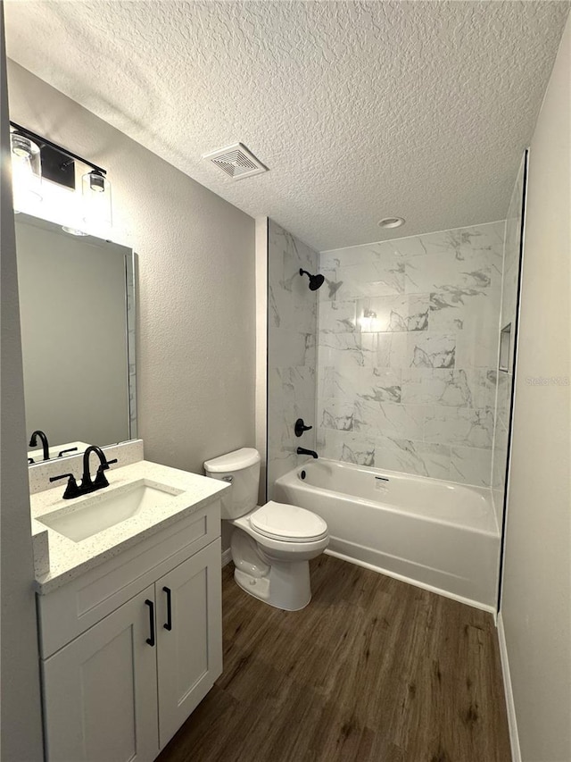 bathroom with toilet, shower / washtub combination, a textured ceiling, visible vents, and wood finished floors