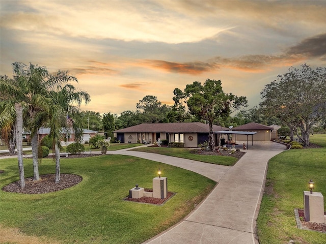 ranch-style house with stucco siding, curved driveway, and a yard