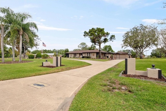 surrounding community featuring concrete driveway and a yard