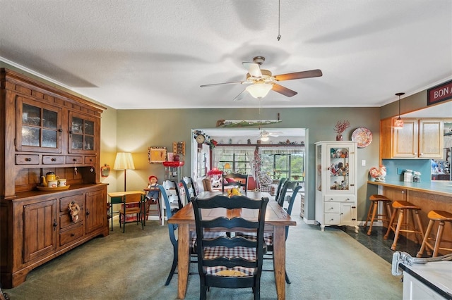 dining space featuring a textured ceiling, carpet flooring, ceiling fan, and crown molding