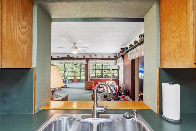 kitchen with a ceiling fan, a sink, and a textured ceiling