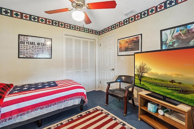 carpeted bedroom featuring a ceiling fan, visible vents, a closet, and a textured ceiling