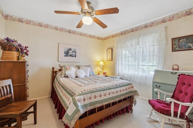 bedroom with light colored carpet, ceiling fan, baseboards, and a textured ceiling
