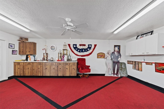 misc room with dark colored carpet, ceiling fan, and a textured ceiling