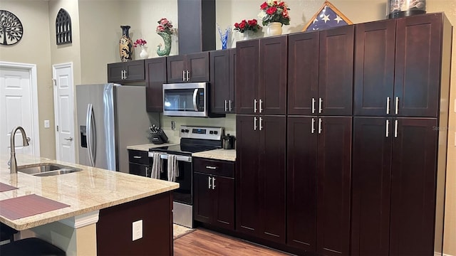 214 Brook Ln, Polk City, FL 33868 - kitchen with light stone counters, a sink, a breakfast bar area, light wood-style flooring, and stainless steel appliances