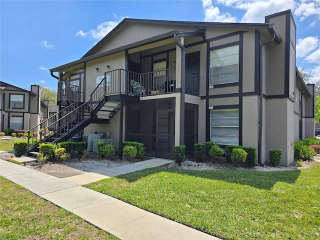 14663 Norwood Oaks Dr Unit 103, Tampa, FL 33613 - view of front facade featuring stucco siding, stairs, central AC, and a front yard