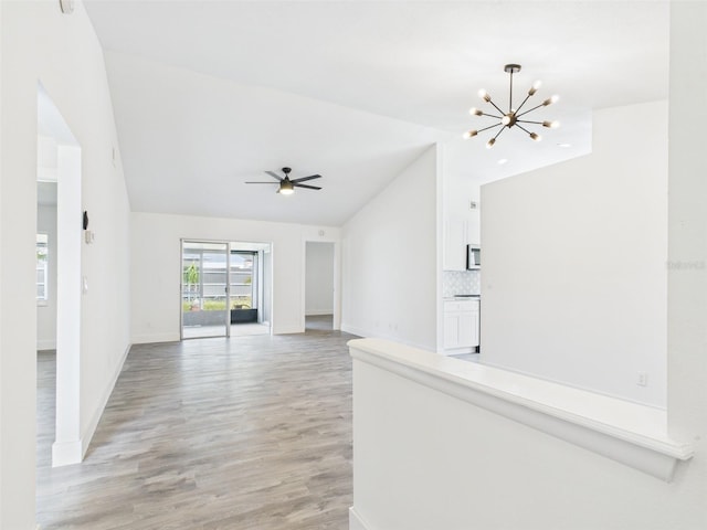 interior space featuring baseboards, high vaulted ceiling, ceiling fan with notable chandelier, and light wood finished floors
