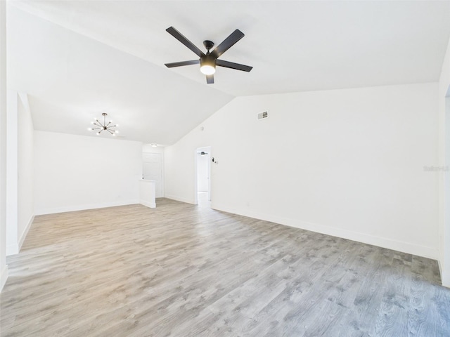 interior space with visible vents, baseboards, lofted ceiling, light wood-style floors, and ceiling fan with notable chandelier
