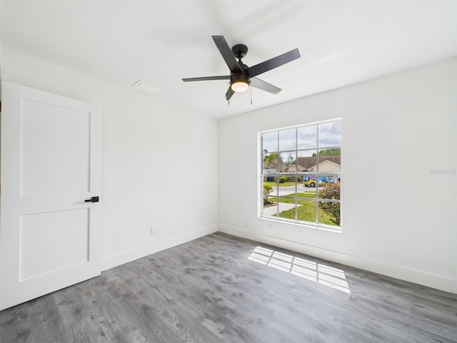 unfurnished room with baseboards, ceiling fan, and wood finished floors