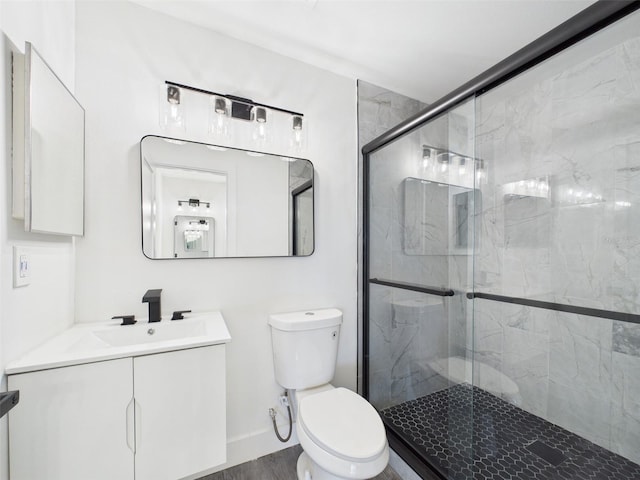 bathroom with a stall shower, toilet, vanity, wood finished floors, and baseboards