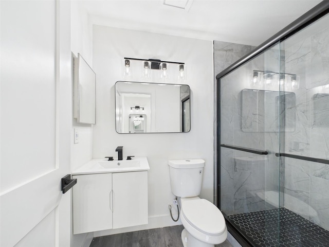 bathroom featuring toilet, vanity, a marble finish shower, and wood finished floors