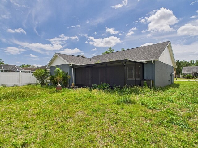 back of property with a sunroom, central AC, and fence