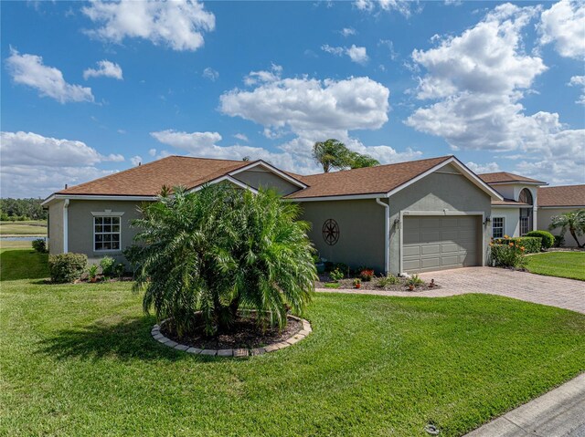 ranch-style home with stucco siding, a front yard, decorative driveway, and a garage