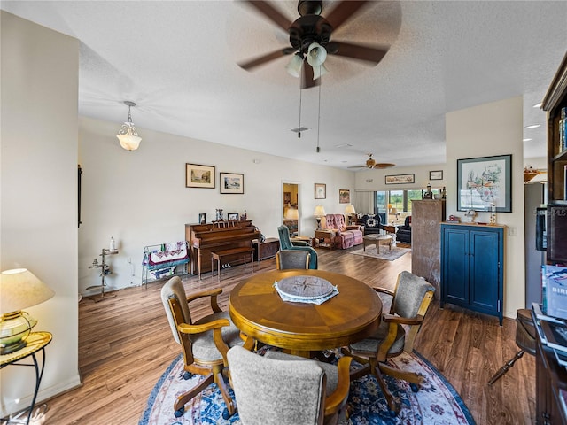 dining area featuring a textured ceiling, wood finished floors, and a ceiling fan
