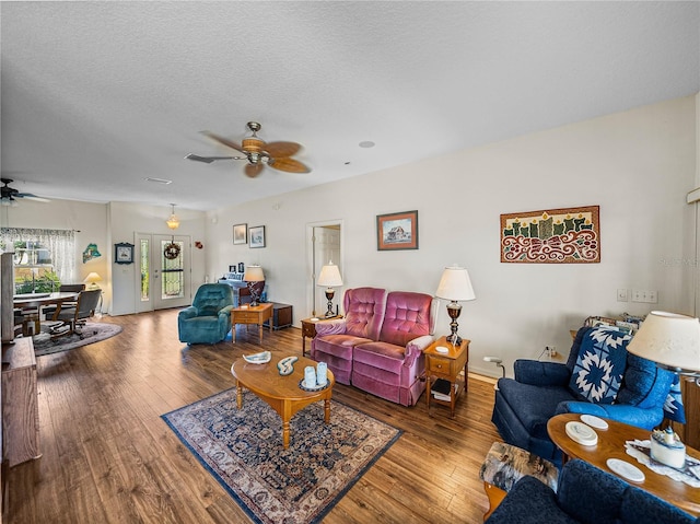 living area with wood-type flooring, a ceiling fan, and a textured ceiling