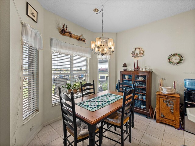 dining space featuring an inviting chandelier, light tile patterned floors, baseboards, and a textured ceiling